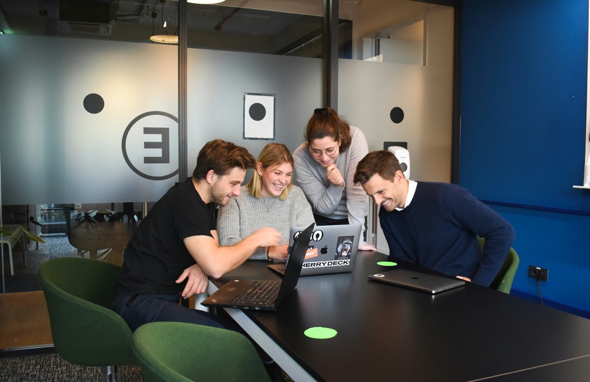 Engineering team collaborating around laptops in a modern office